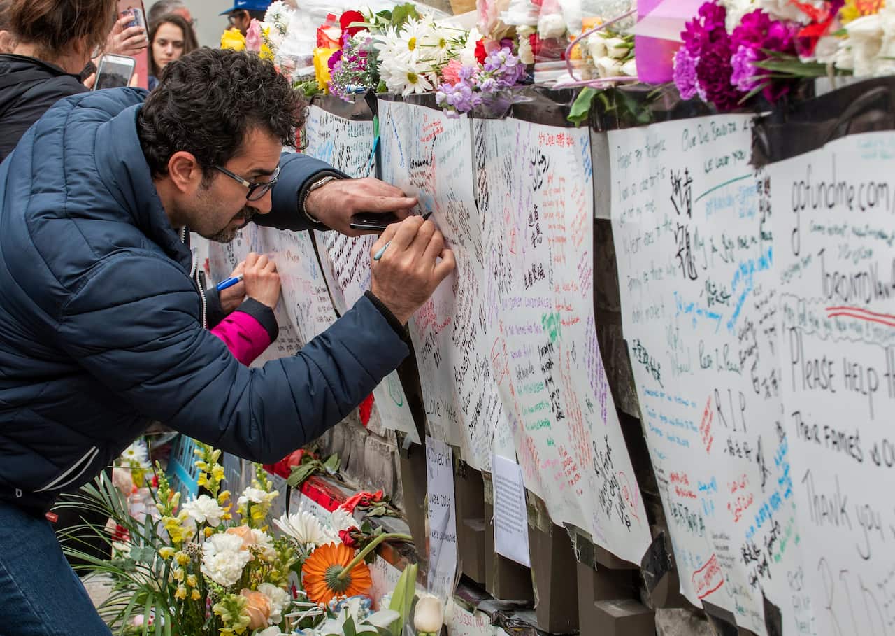 A man writes a message at a makeshift memorial across the street from where a man in a rented van plowed into pedestrians in Toronto, Canada.