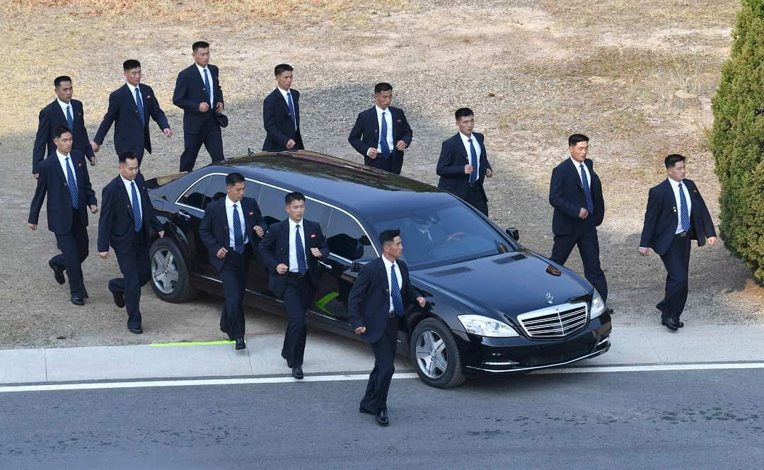 North Korean security persons run by a car carrying North Korean leader Kim Jong-un.