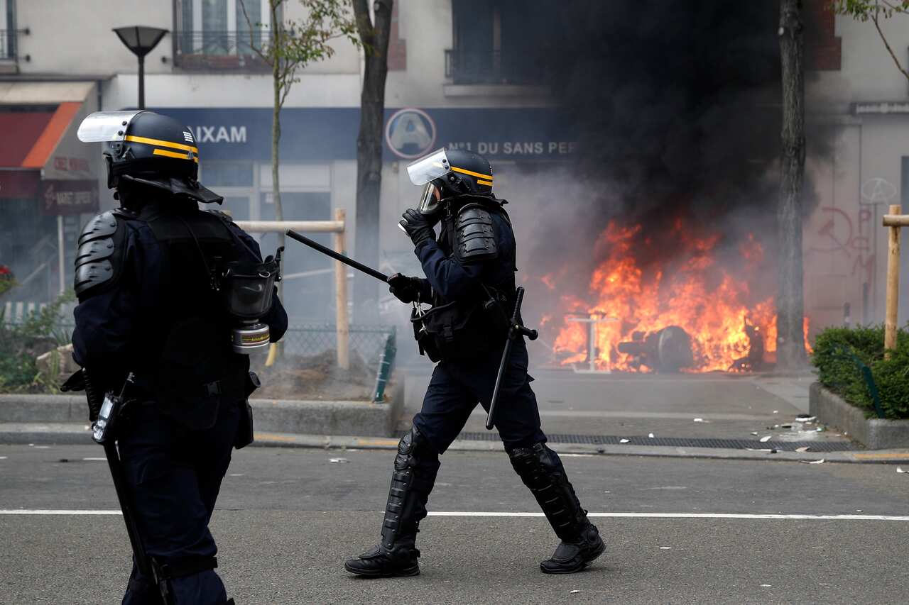 French riot police forces pass a fire while patrolling a street as clashes broke out between protesters and French police forces during a demonstration of workers from the private and public sectors as well as labor unions.
