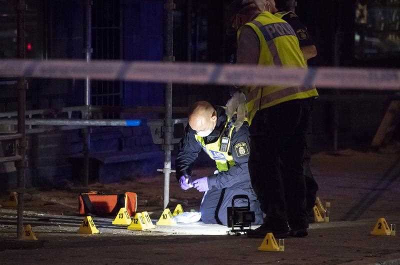 Forensics police officers investigate the scene after six people were shot and injured
