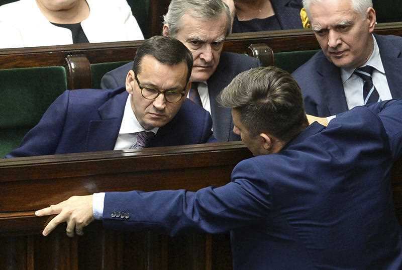 Polish Prime Minister Mateusz Morawiecki talks with a lawmaker during a parliament debate on changes to the controversial Holocaust law