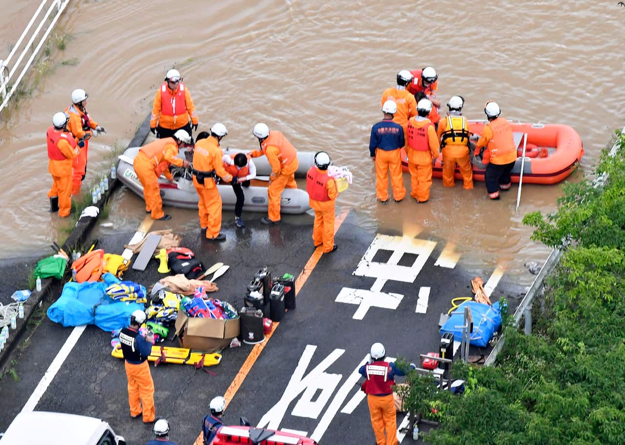 Fire fighters helps residents to get off boats in Kurashiki, Okayama Prefecture on July 7, 2018. 