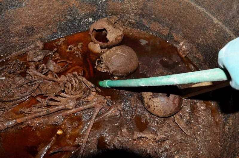 Workers removing sewer water submerging three decomposed mummies after opening the black granite sarcophagus.