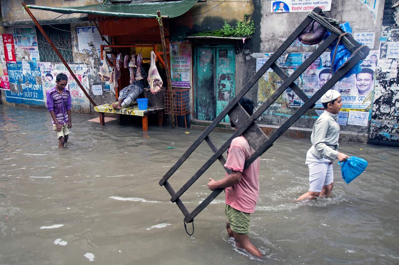 epa06907869 Bangladeshi people walk on the street submerged by rainwater in Old Dhaka city, Bangladesh, 24 July 2018. Heavy monsoon rains flooded parts of the capital. EPA/MONIRUL ALAM
