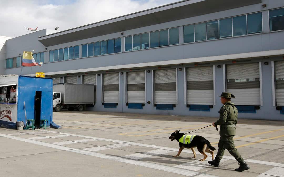 Handler Jose Rojas and drug dog Sombra patrol outside the cargo hold of El Dorado airport in Bogota, Colombia.