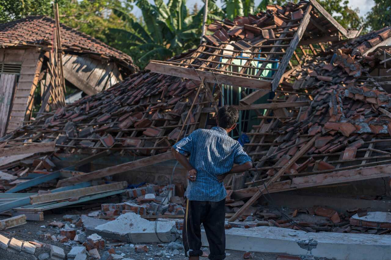 A man inspects the ruins of houses at a village affected by Sunday's earthquake in Kayangan, Lombok Island, Indonesia, Aug. 7, 2018. (AP Photo/Fauzy Chaniago)