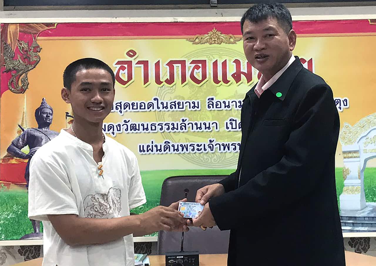 A member of the Wild Boar soccer team Adul Sam-on (L) as he receives his Thai citizen ID card