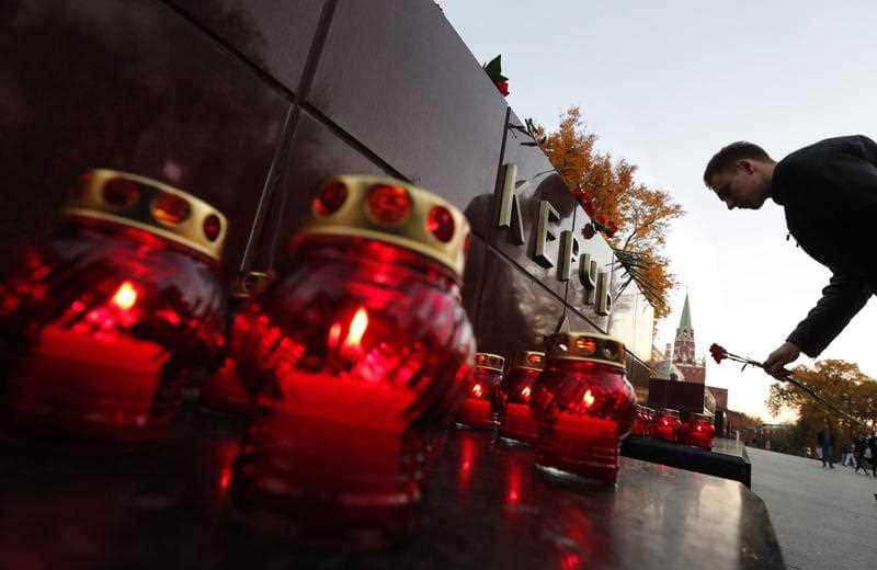 A man lays flowers as a sign of mourning for the dead children at a vocational school in Kerch in Crimea.