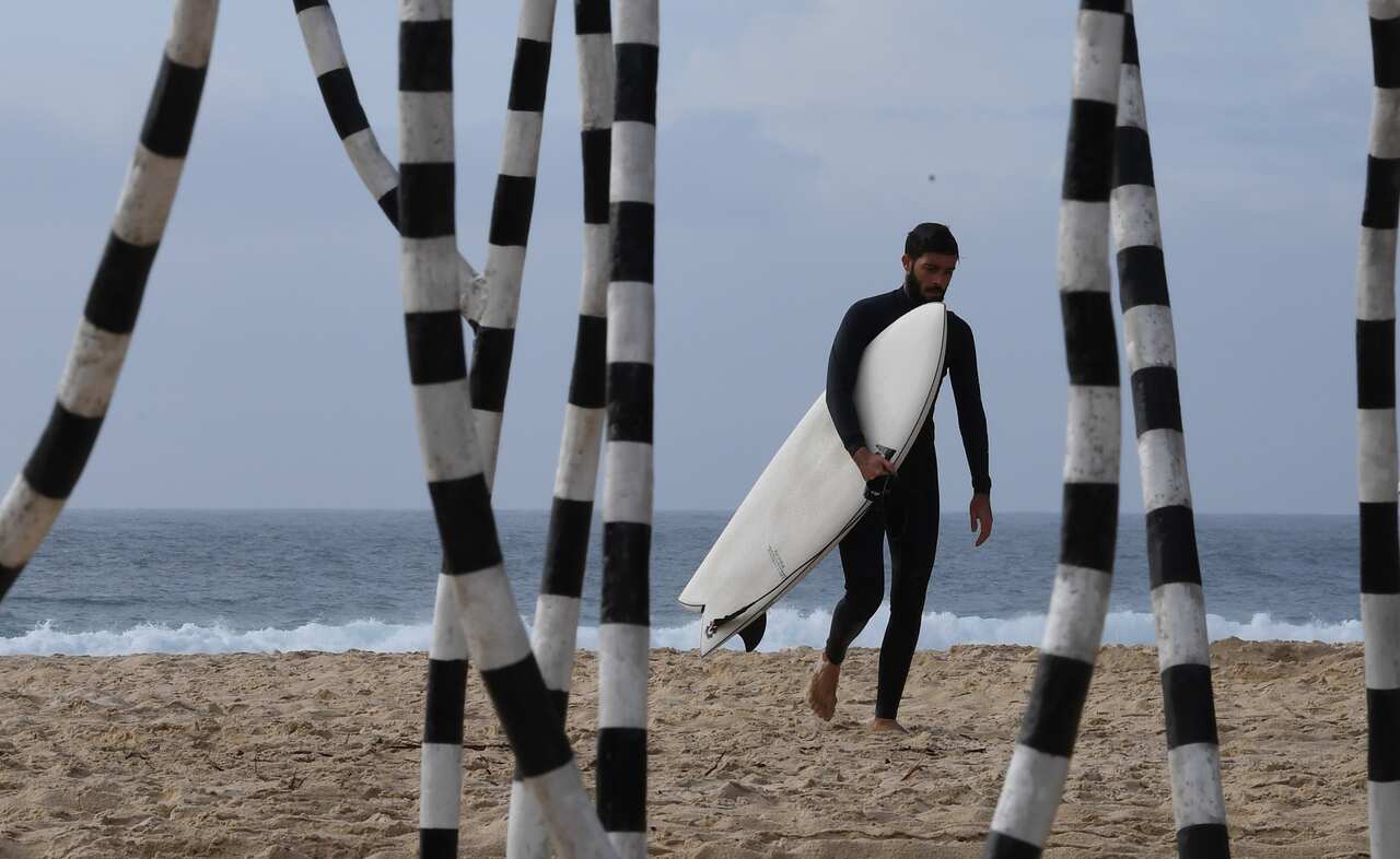 A surfer walks past The Sculpture Configuration by WA artist Kevin Draper.
