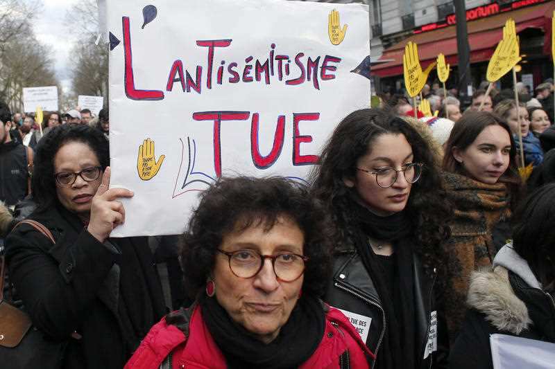 A woman in Paris holds a poster reading : "the anti-semitism kills" 