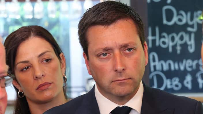 Victorian Leader of the Opposition Matthew Guy speaks to the media while his wife Renae Guy (left) watches on Monday, November 19, 2018.