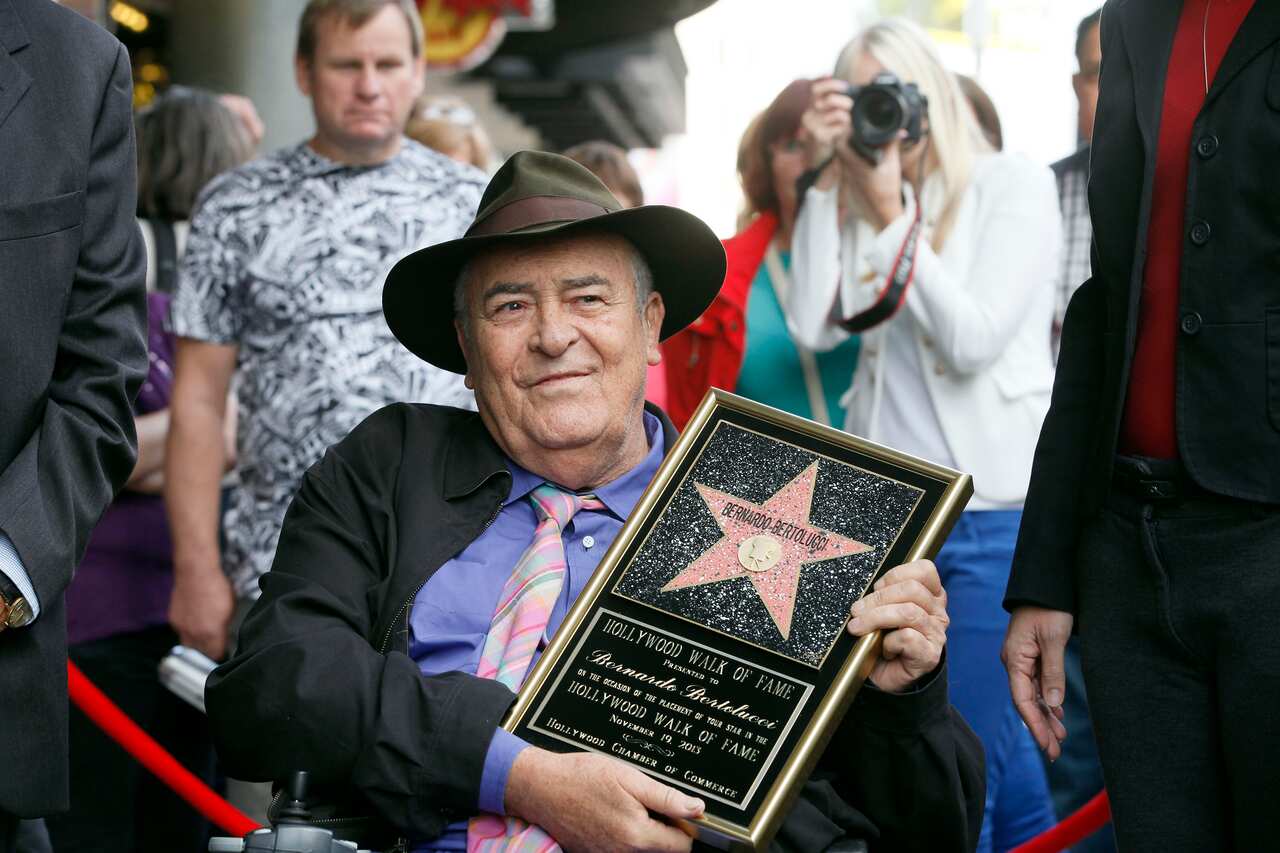 Italian director Bernardo Bertolucci holds a star plaque at a ceremony in his honor as he makes a rare visit to his star on the Hollywood Walk of Fame.