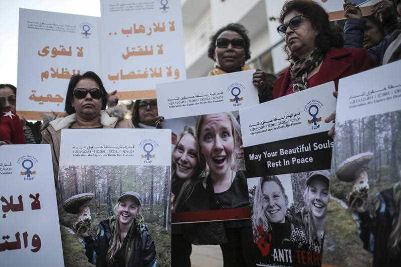 Moroccan women carry photos of Maren Ueland and Louisa Vesterager Jespersen outside the Danish embassy in Rabat