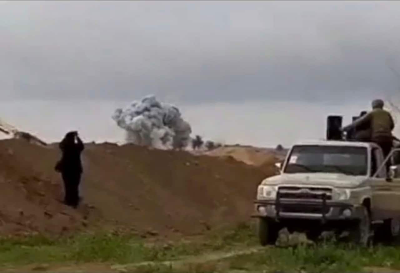 U.S.-backed Syrian Democratic Forces fighters looking at smoke rising.