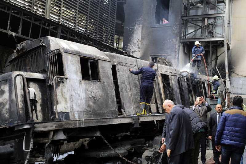  Firefighters extinguish flames and cool off a train engine after a fire broke out on tracks at the main train station in Cairo