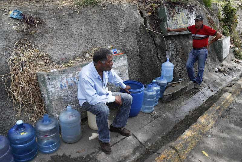 Men fill containers with water at Avila National Park during rolling blackouts