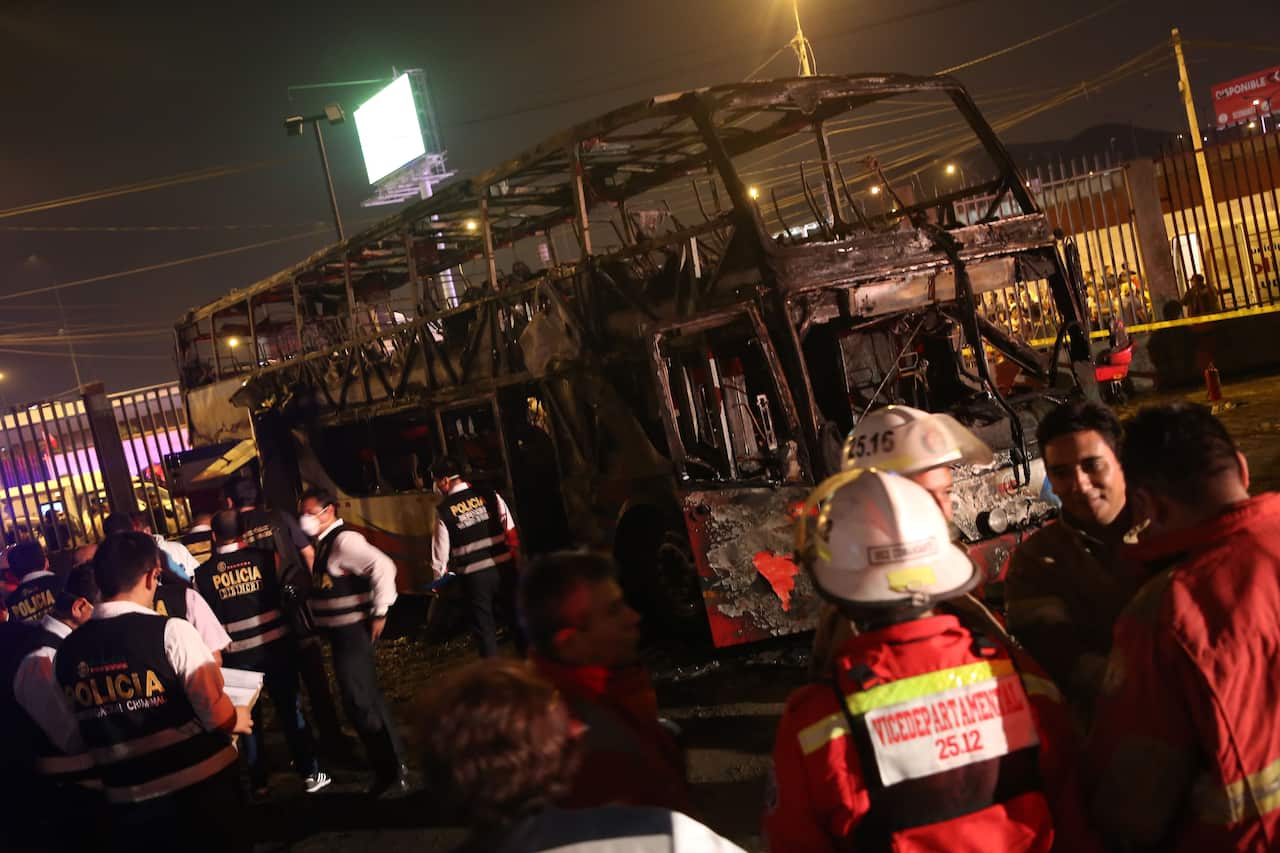 Firefighters and police inspect the charred remains of the bus.