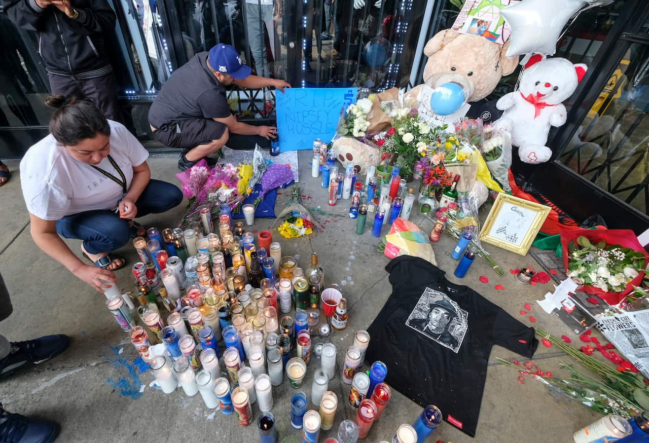 Fans of rapper Nipsey Hussle appear at a makeshift memorial in the parking lot of Hussle's Marathon Clothing store in Los Angeles, Monday, April 1, 2019. Hussle was killed in a shooting outside the clothing store on Sunday. (AP Photo/Ringo H.W. Chiu)