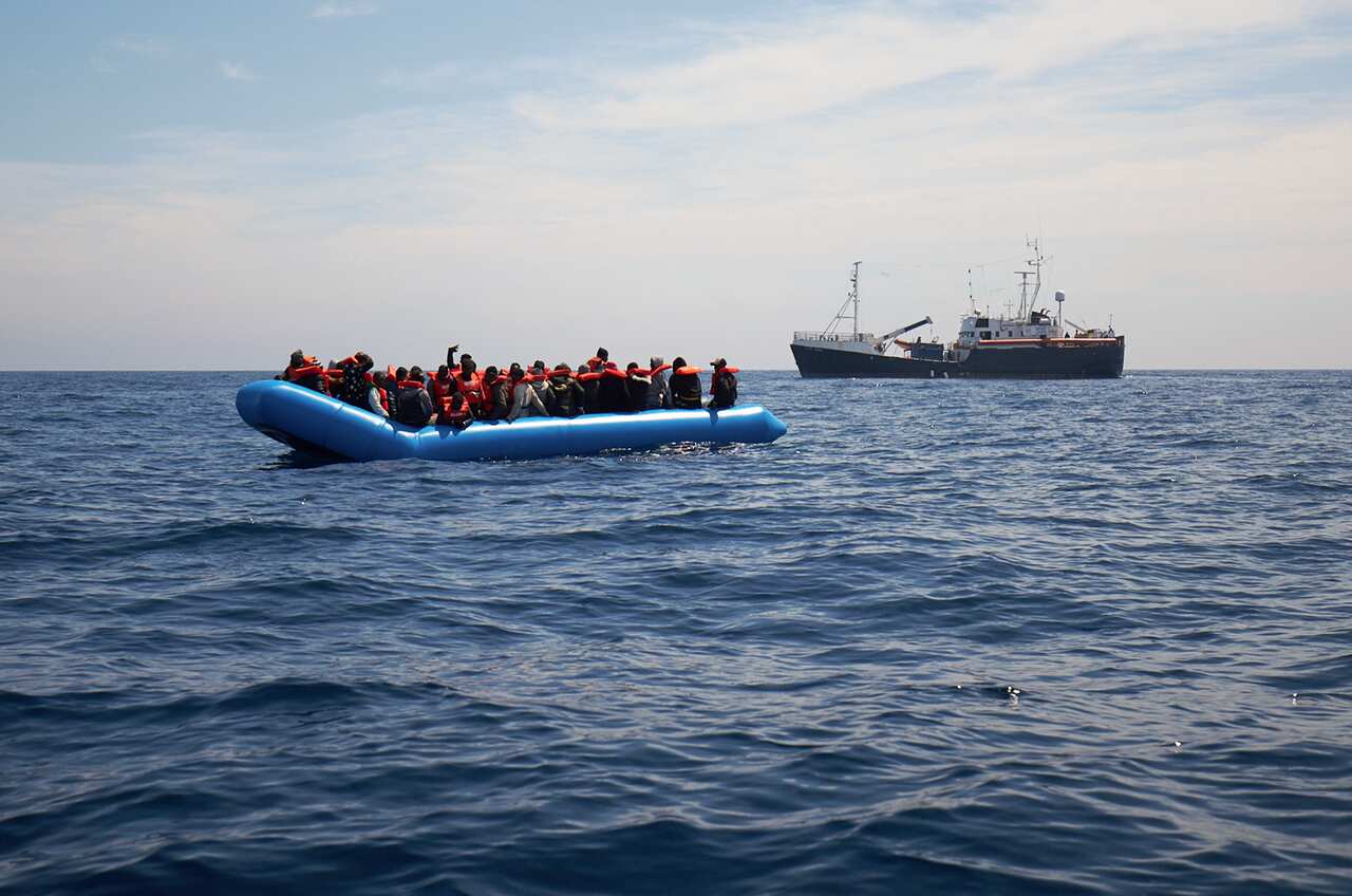 Migrants on a rubber dinghy are approached by the Sea-Watch rescue ship