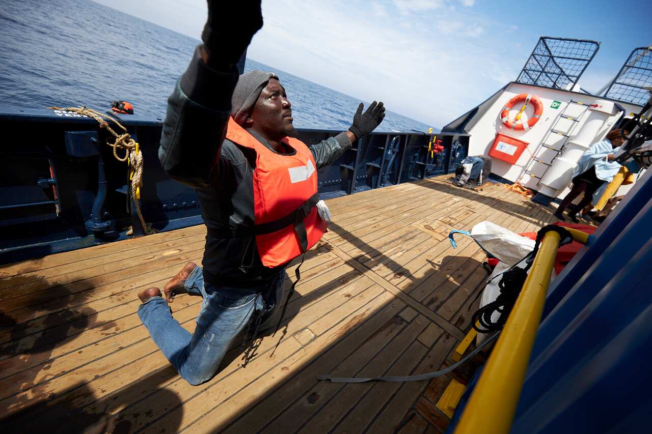 A man prays on the dock of the Sea-Watch rescue ship