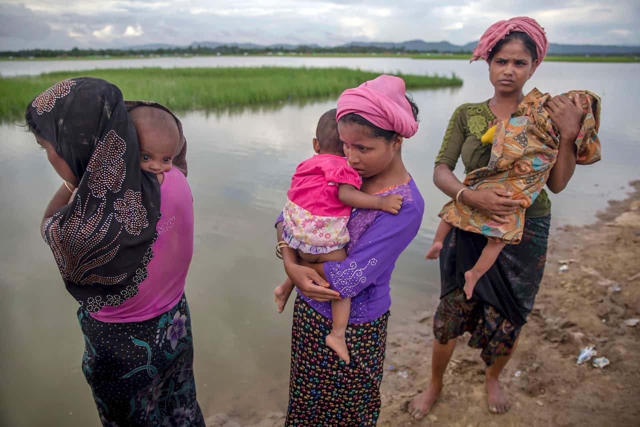 Rohingya Muslim women, who crossed over from Myanmar into Bangladesh, hold their sick children.
