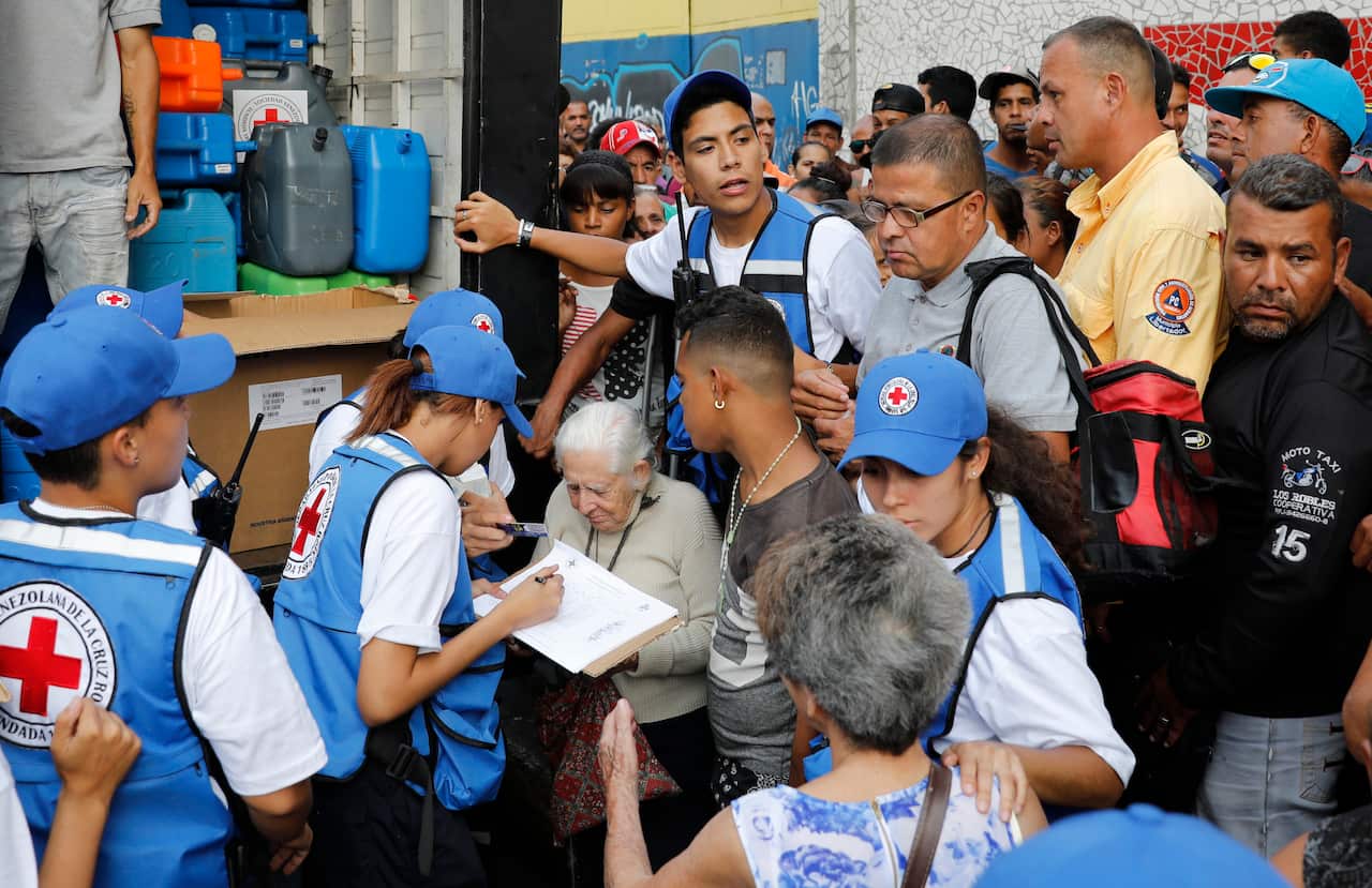 People register to be given empty water containers and water purification pills during the Red Cross' first aid shipment in Caracas, Venezuela.