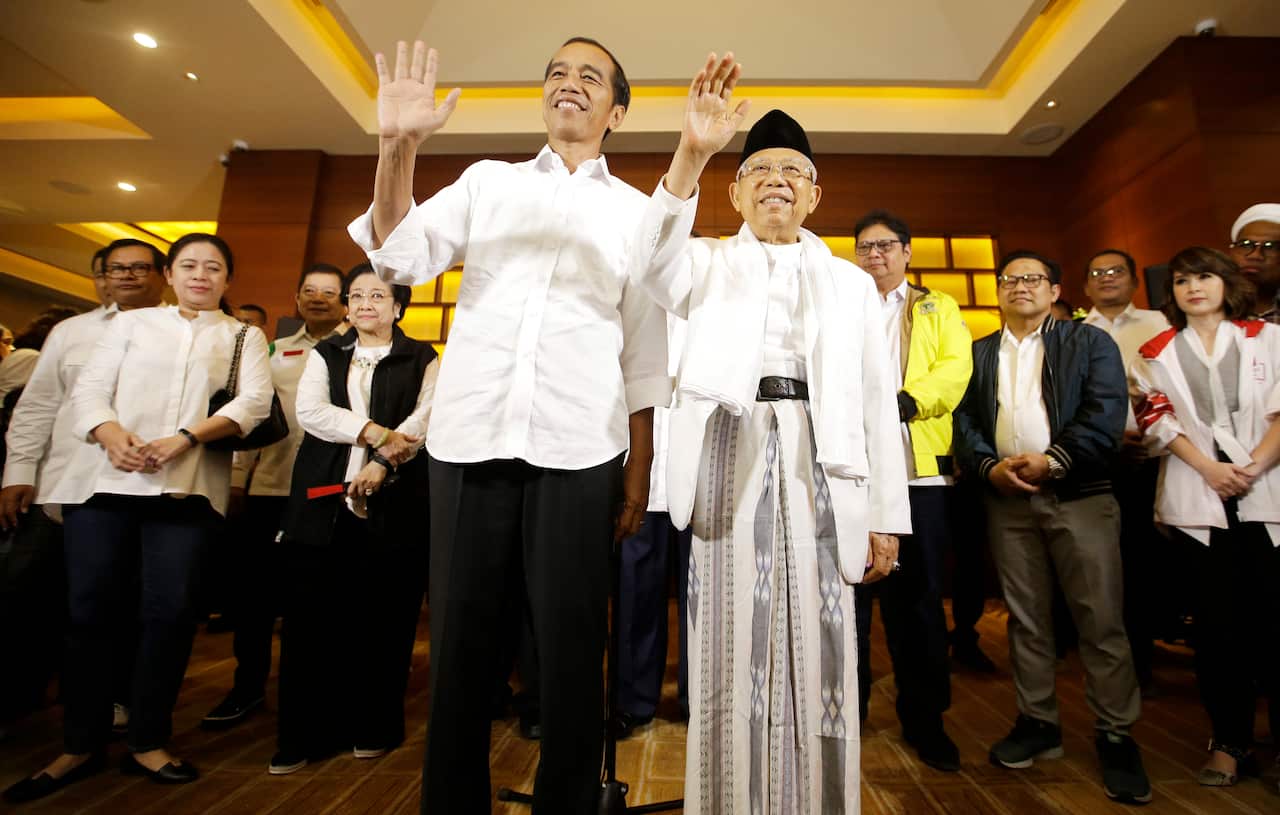 Indonesian President Joko Widodo and his running mate Ma'ruf Amin, right, wave to journalist after a press conference in Jakarta, Indonesia.