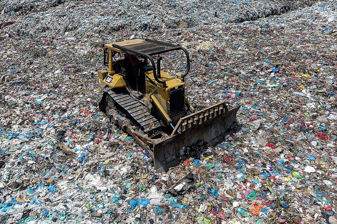 A bulldozer seen working to move piles of waste at a garbage dumps in Lhokseumawe, Aceh province, Indonesia.