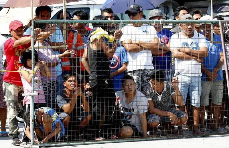 Residents watch as rescuers continue to search for survivors following Monday's 6.1 magnitude earthquake.