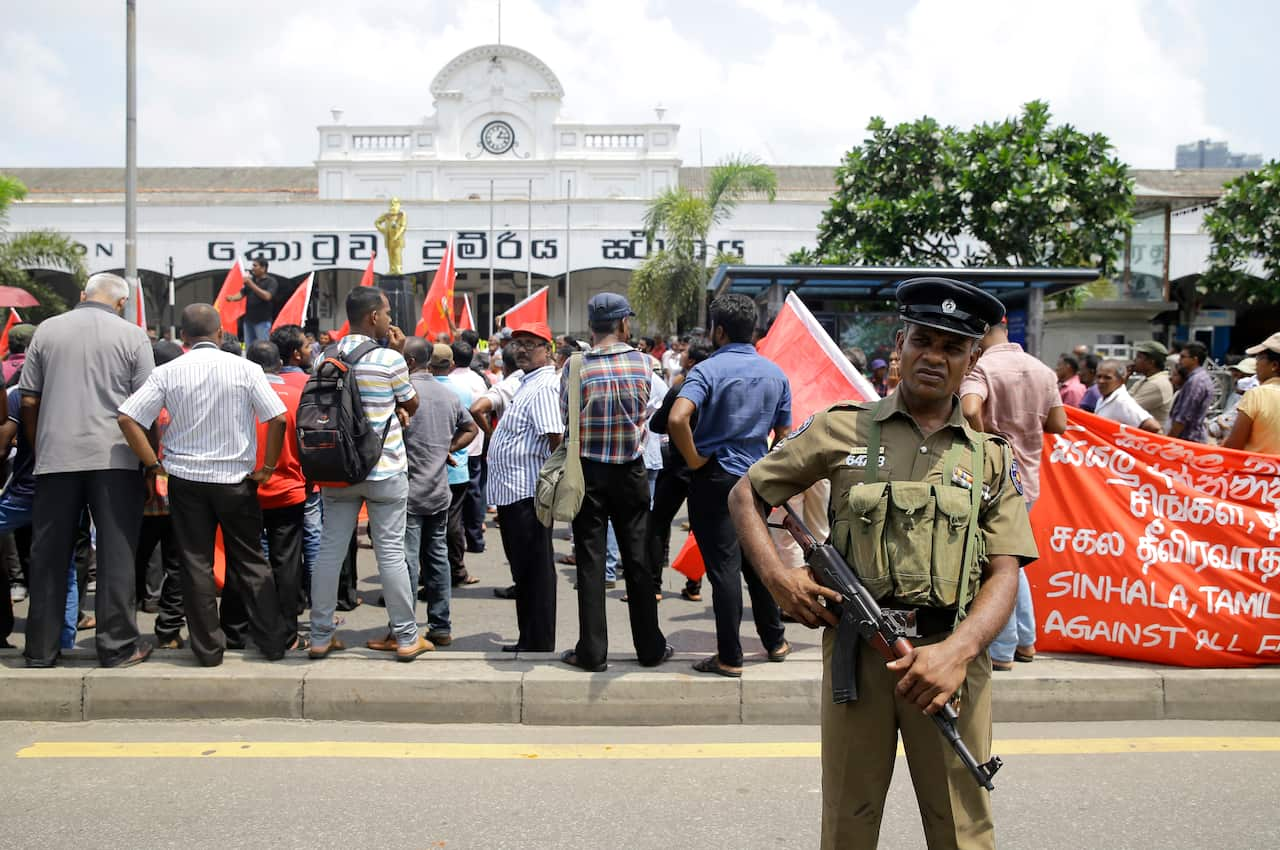 A Sri Lankan police officer secures the area of a labor day gathering.