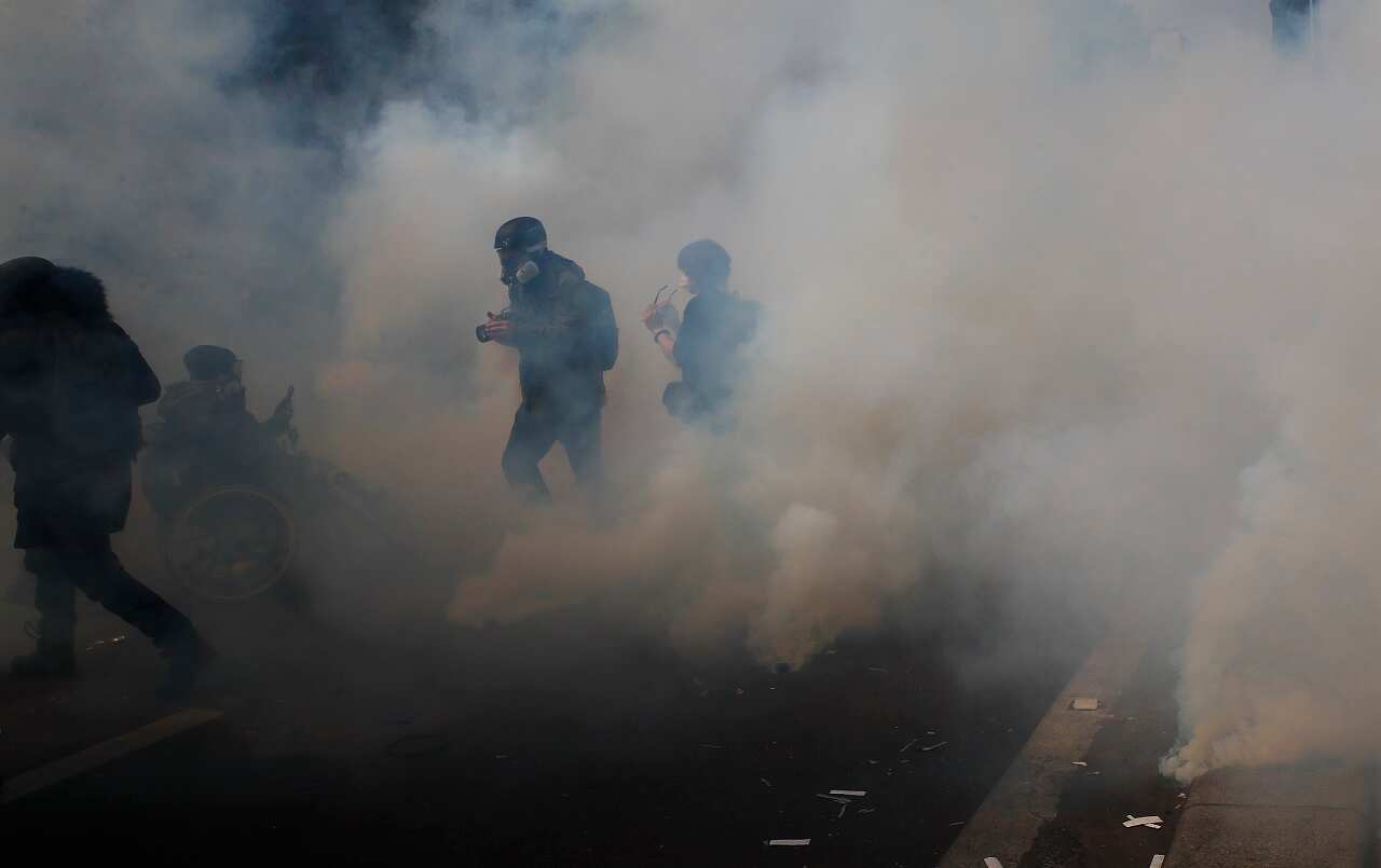 Activists run away from tear gas during a May Day demonstration in Paris.