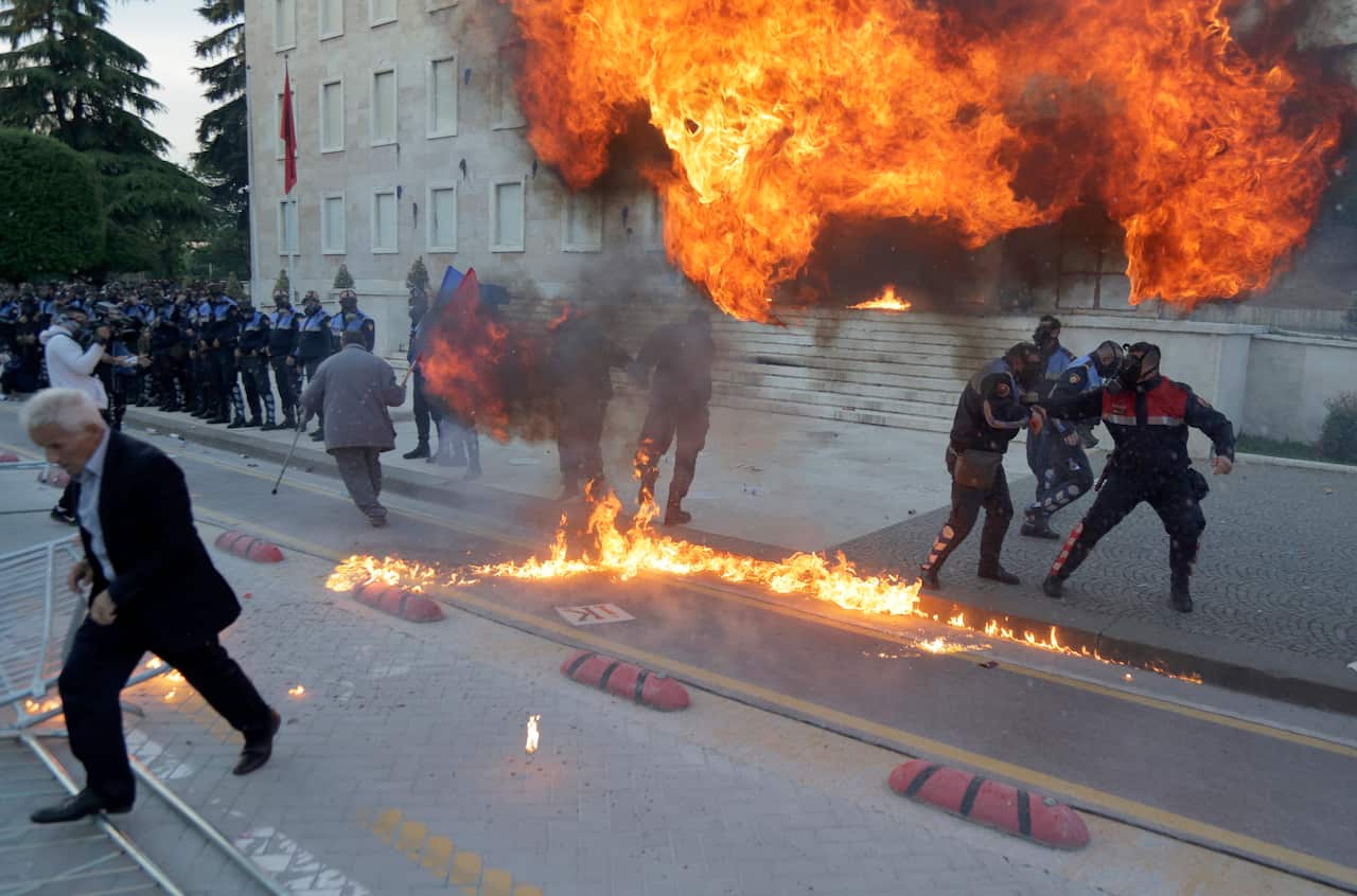 Policemen try to avoid exploding Molotov bombs thrown by protesters, during a protest in Tirana, Albania.