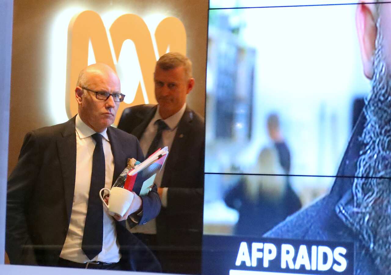 John Lyons (left), Executive Editor of the ABC News, is followed by an Australian Federal Police officer at the ABC building located at Ultimo in Sydney.