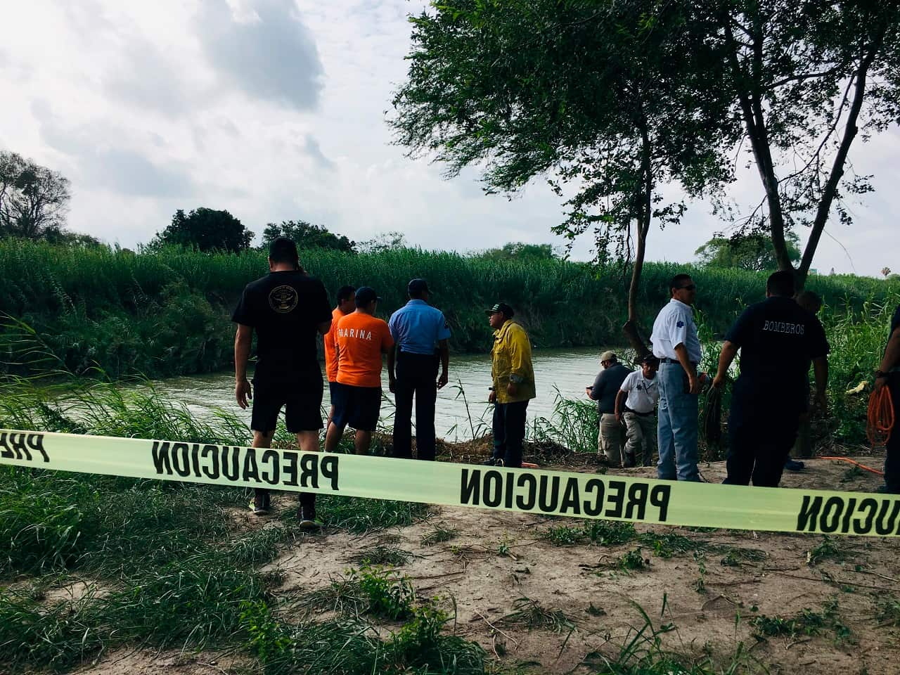 Authorities stand behind yellow warning tape along the Rio Grande.