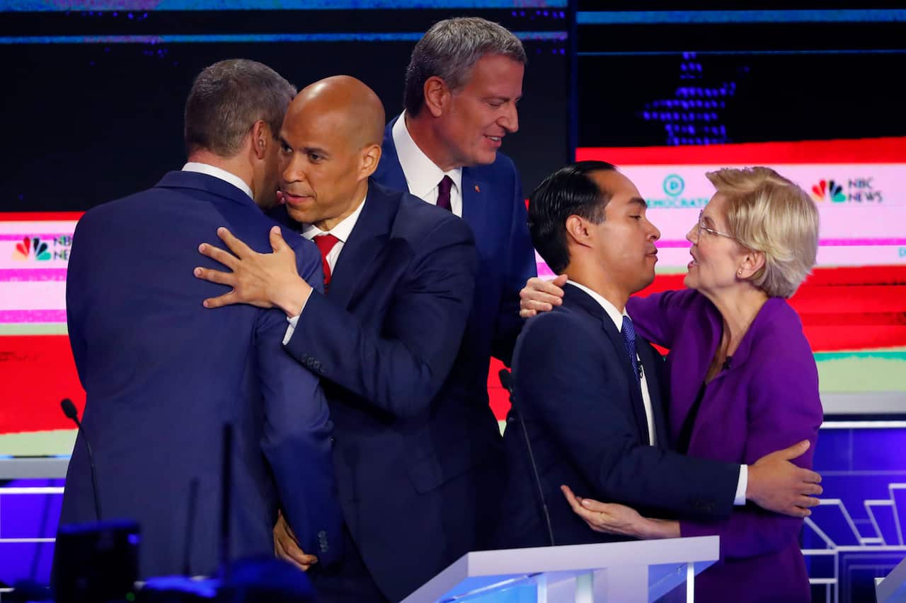 New Jersey Senator Cory Booker hugs US Representative Tim Ryan and Massachusetts Senator Elizabeth Warren hugs Former Housing Secretary Julian Castro.