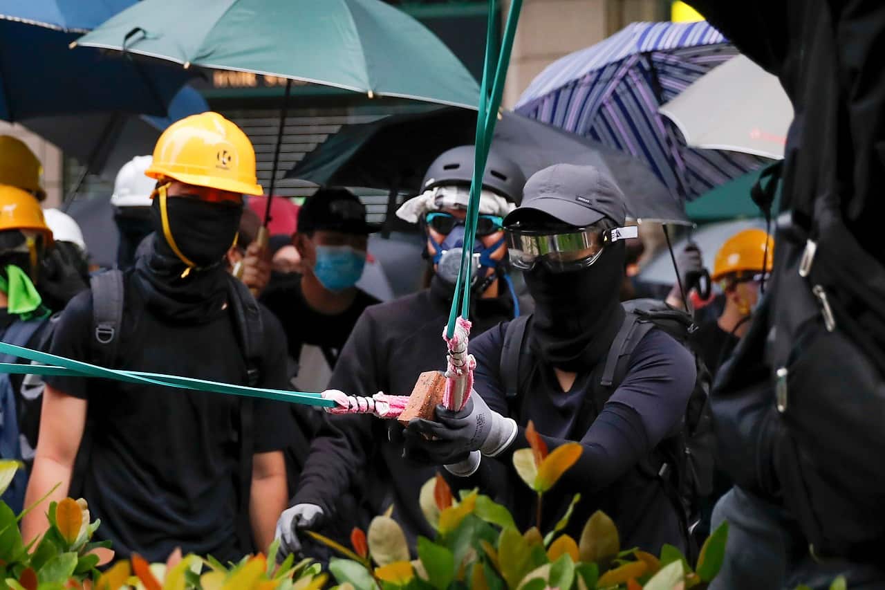Protesters using sling shot to bricks at a police station.