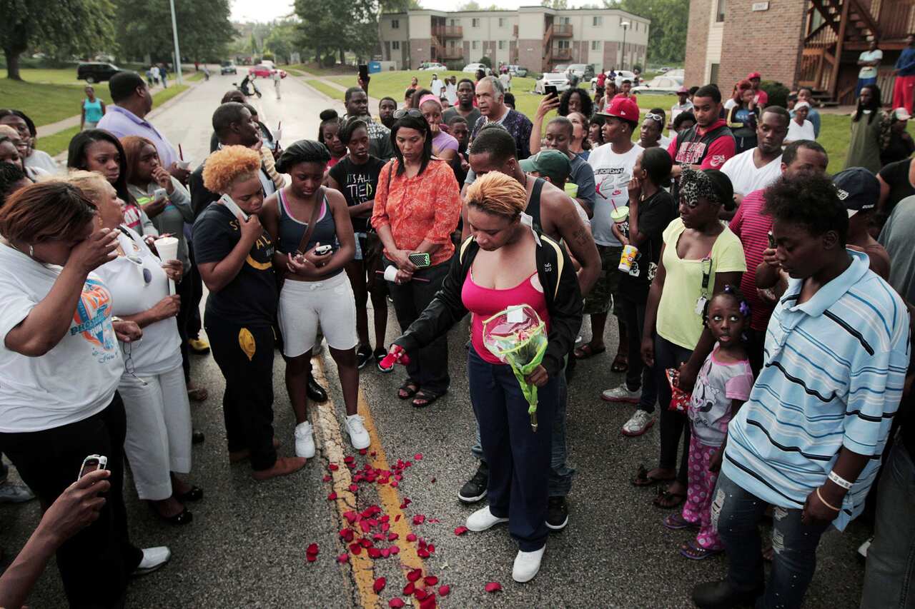 Michael Brown's mother scatters rose petals over the road on which her son was killed.