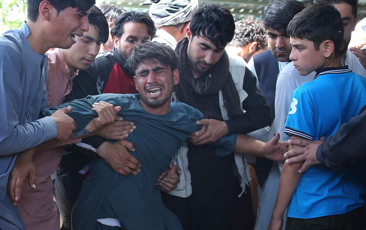 Relatives grieve near the coffins of victims of the Dubai City wedding hall bombing during a mass funeral in Kabul, Afghanistan.