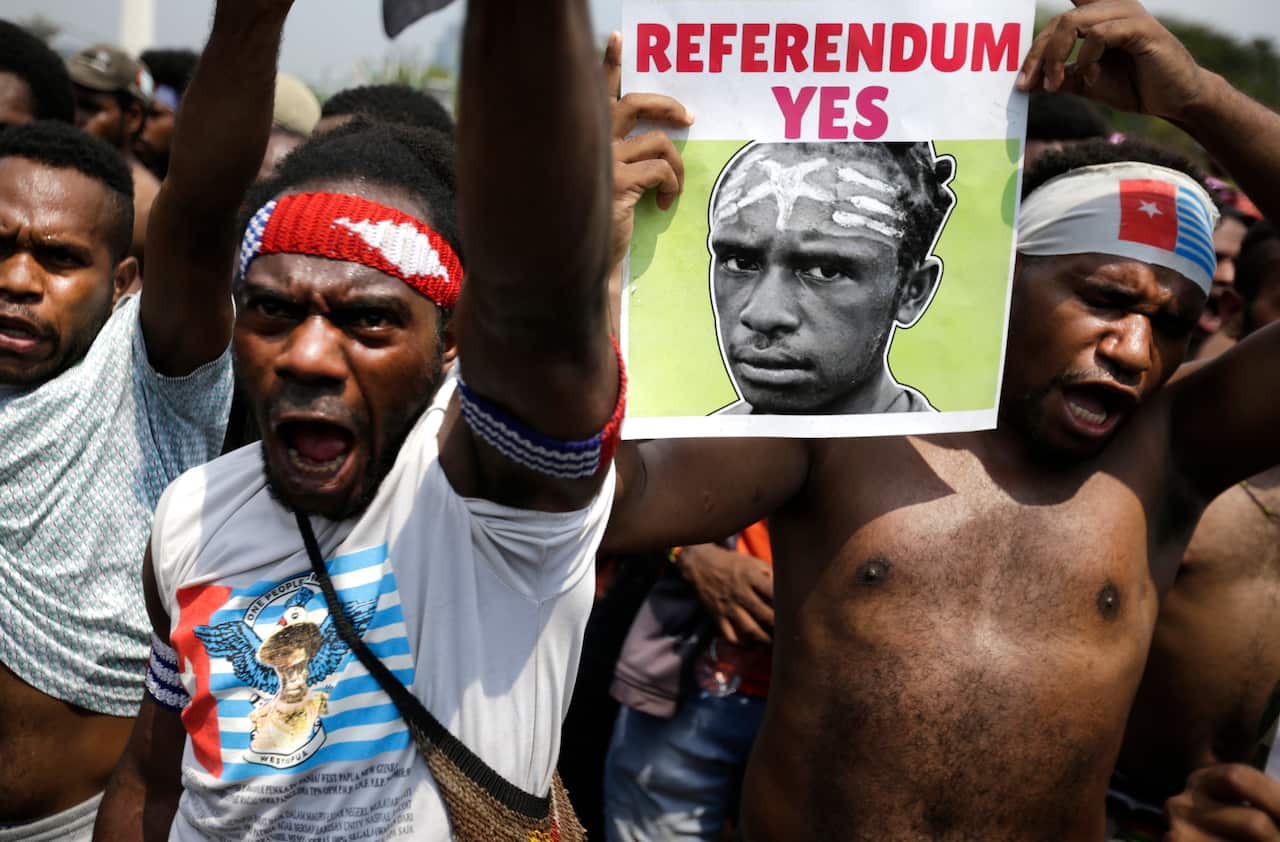 A Papuan activist displays a banner demanding referendum during a rally near the presidential palace in Jakarta, Indonesia.