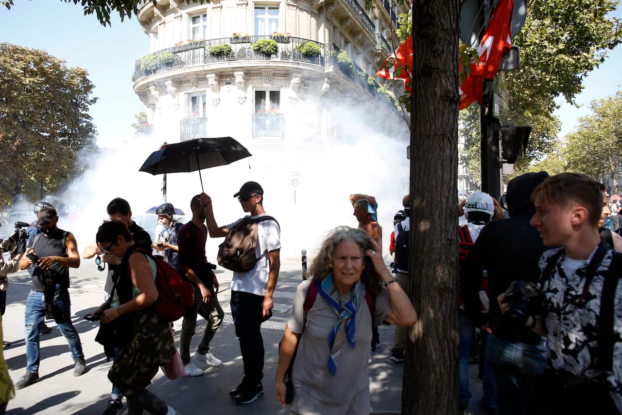 Protesters stand in a smoke of teargas during a climate demonstration, in Paris.