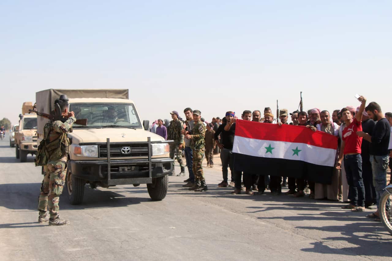 People welcome Syrian troops as they enter the village of Ghebesh, west of the town of Tal Tamr, in northern Syria on Monday.