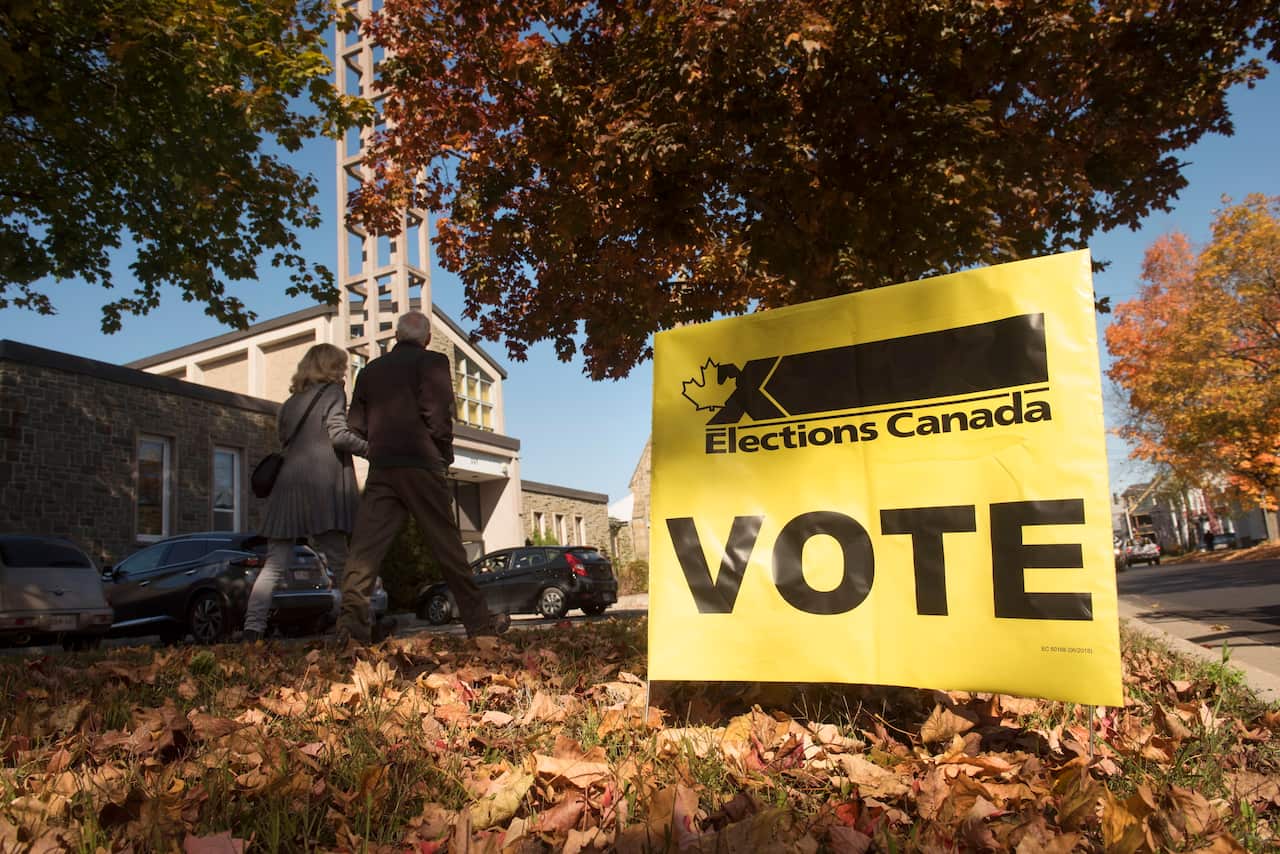People walk toward the entrance to Christ Church (Parish) Church, where they can vote in the federal election in Fredericton, Monday, Oct. 21, 2019. (Stephen MacGillivray/The Canadian Press via AP)