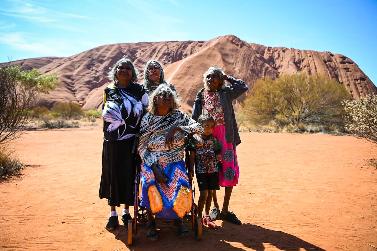 Traditional owners pose for photographs in front of Uluru.