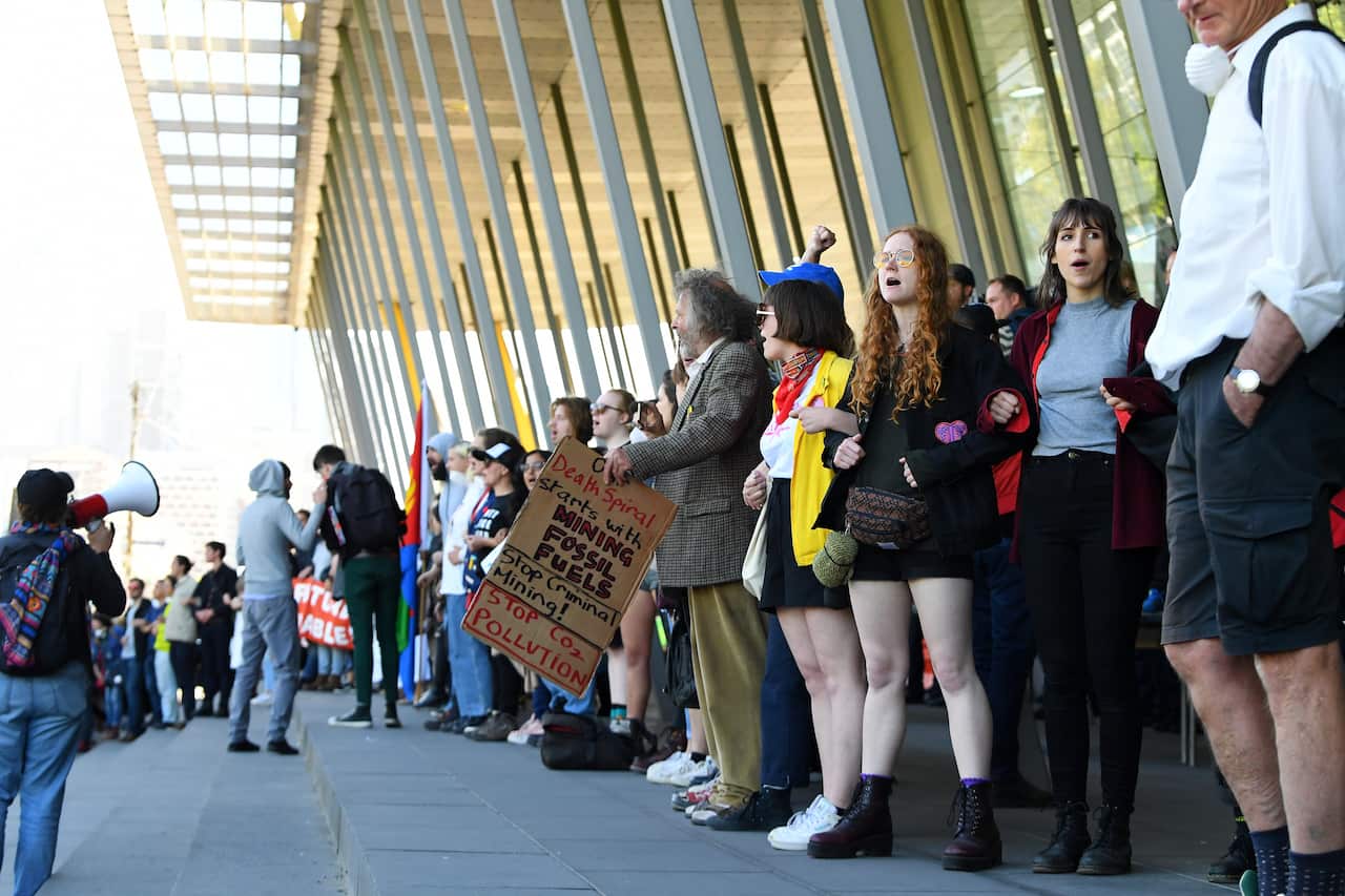Activists link arms to block an entrance to the Melbourne Exhibition and Convention Centre, Melbourne, Tuesday, October 29, 2019.