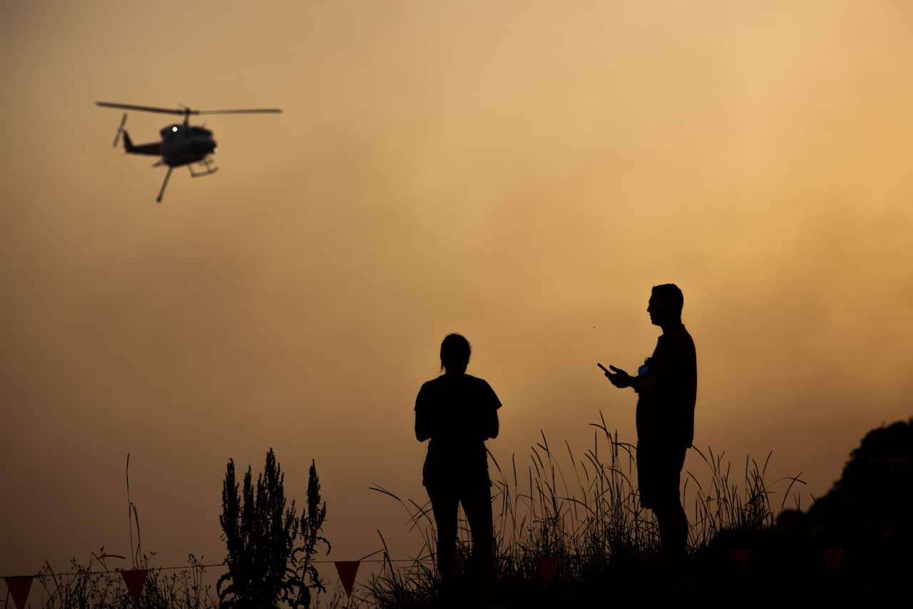 A water bombing helicopter is seen through a smoke haze in Forster, NSW mid-north coast.