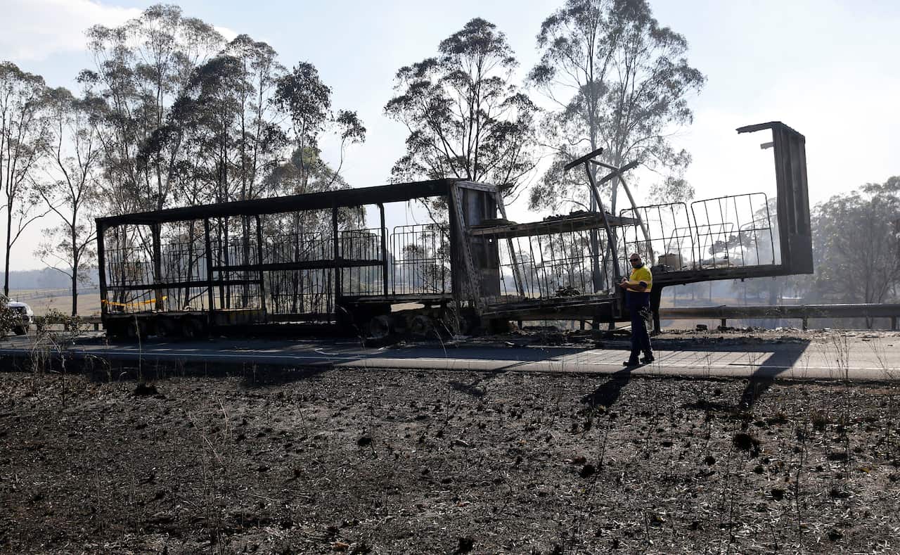 The remains of a B Double trailer smoulders on the Pacific Highway south of  Taree, Saturday, November 9, 2019.  (AAP Image/Darren Pateman) NO ARCHIVING, EDITORIAL USE ONLY