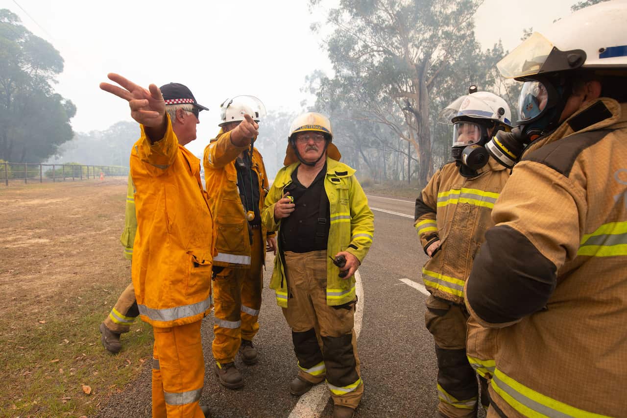 Firefighters discuss tactics near fires at Lake Cooroibah Road. 
