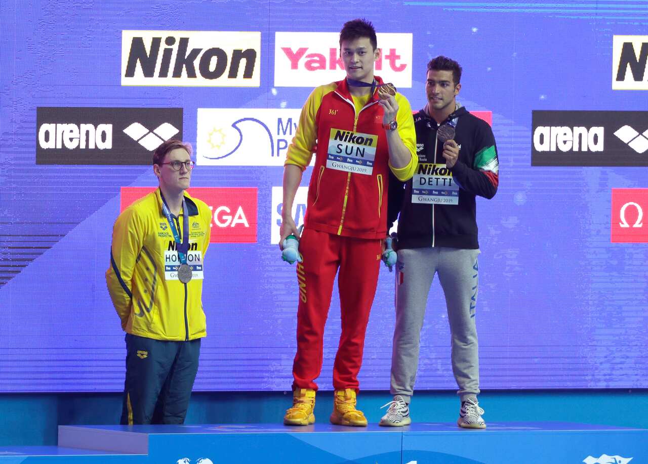 China's Sun Yang holds up his gold medal as silver medalist Australia's Mack Horton, left, stands away from the podium at the World Swimming Championships.