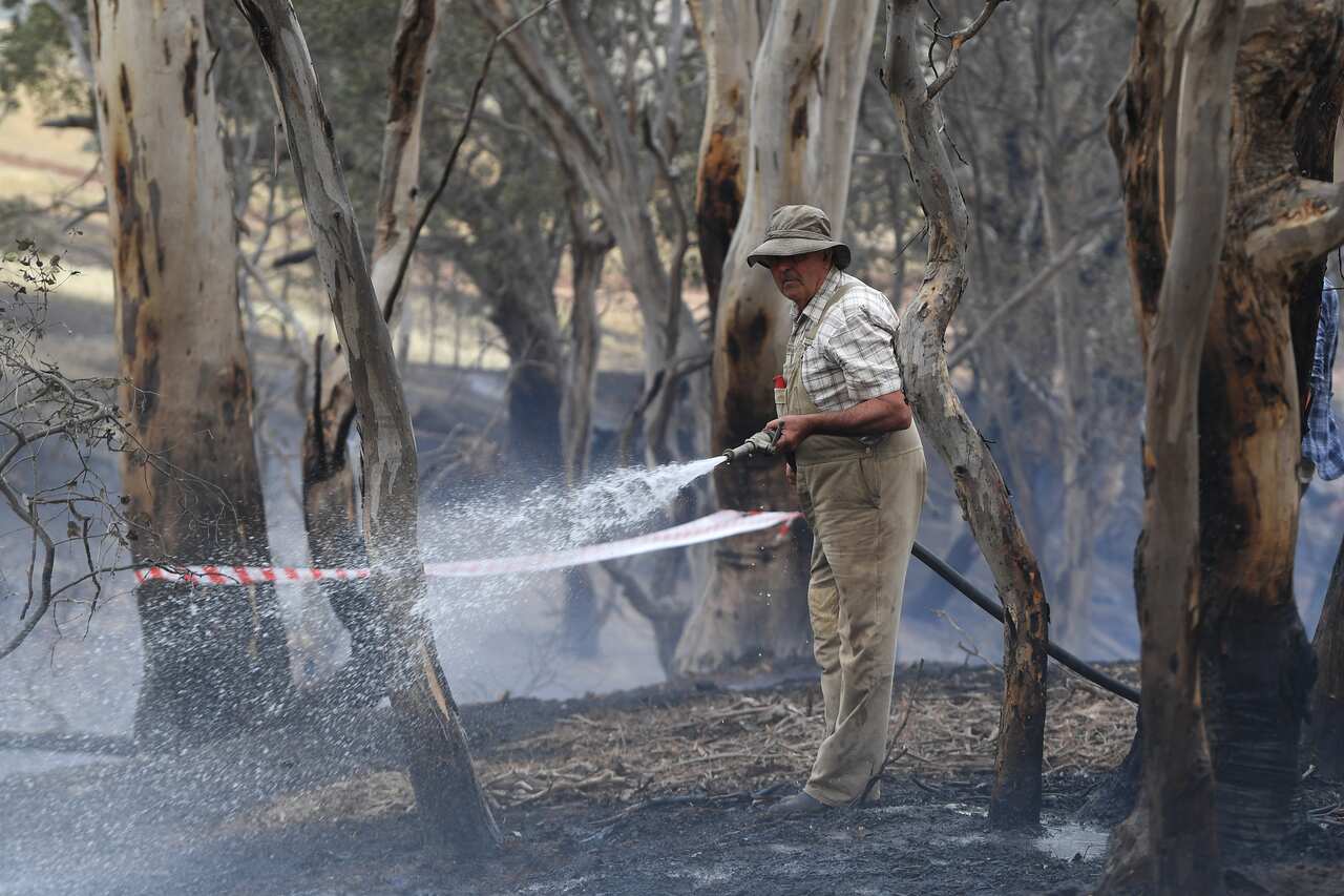 Tom Davies sprays water onto smouldering bushland at Mount Glasgow, Victoria.