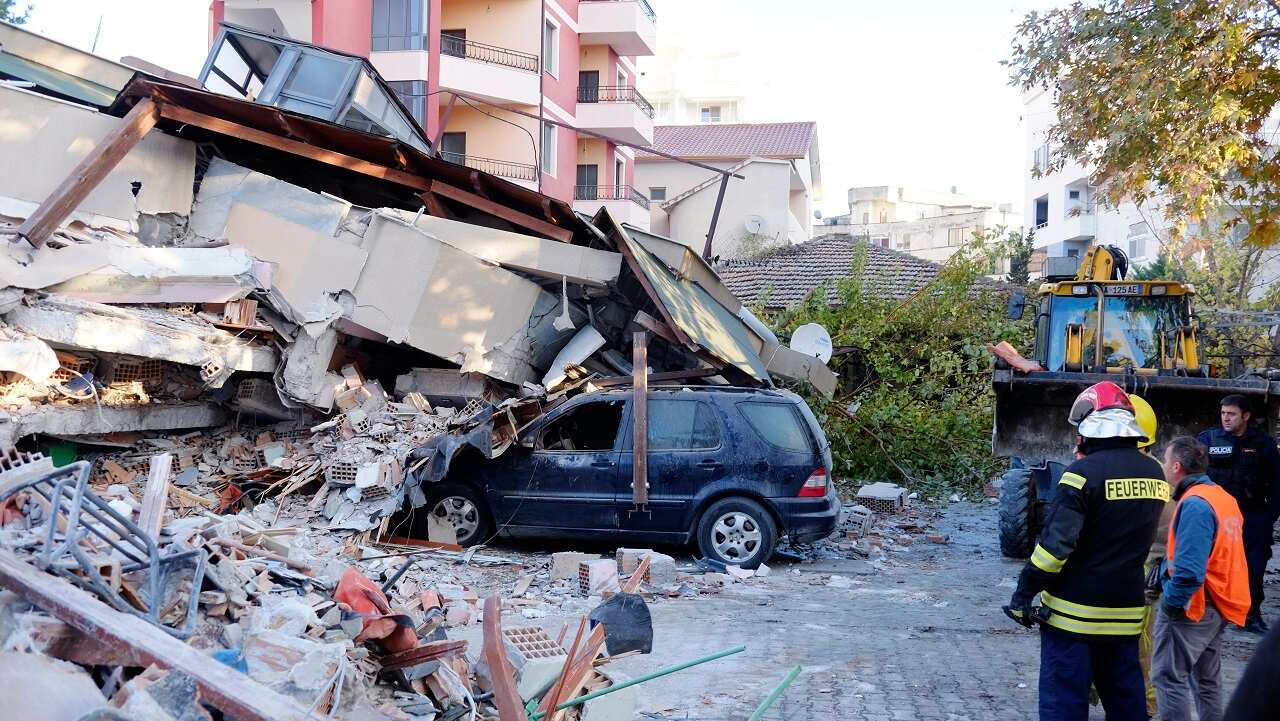 Firefighters stand next to a damaged building after the earthquake.